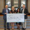 four people holding a large check