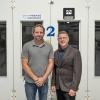 two men pose in collision repair lab