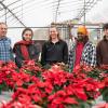 group photo of PLNA rep and four student scholarship recipients in a poinsettia-filled greenhouse