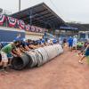 With the practiced hands of veteran tarp-pullers, the Wildcat baseball team goes into action.