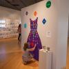 A young visitor enjoys an “interactive dress” on which felt shapes can be added to create a design; some of the shapes offer positive words: honesty, respect, kindness, empathy and patience.