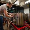 A brewing and fermentation science student works with the stainless steel brewing tanks in the industry-standard instructional space at Penn College. 