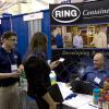 A Penn College student takes a business card from Ring Container Technologies, a Hanover firm on campus to talk with manufacturing engineering technology majors.