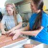 Students Cassandra B. Mohr, left, and her roommate Paige E. Monk, handle pans of meatloaf.