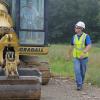 Diesel equipment technology instructor Chris S. Weaver provides walk-along guidance to a young man operating a crawler excavator.