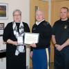 Beside an office wall that reflects her affiliation with Little League Baseball, Pennsylvania College of Technology President Davie Jane Gilmour is presented with the Commander's Award for Public Service by Bison Battalion's Lt. Col. Daniel B. George (center) and Briton D. Orndorf, battalion liaison officer.