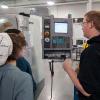 Penn College student Brian J. Pernot, who is studying manufacturing engineering technology, shows Williamsport Area Middle School students the workings of automated manufacturing on a Haas computer-numeric-controlled vertical machining center.